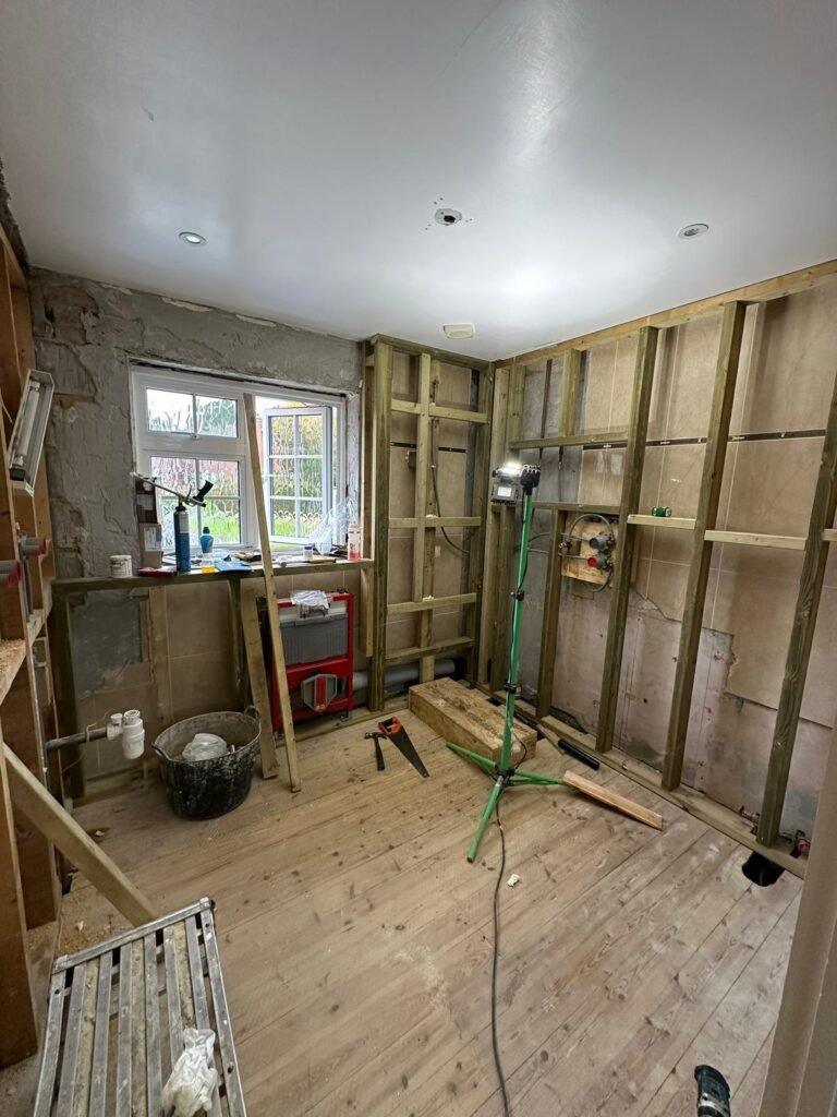 Bathroom renovation in progress with timber stud walls, wall-hung toilet frame, and shower mixer valve plumbing.