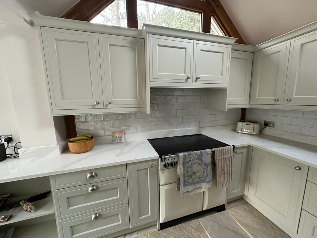 Finished grey Shaker kitchen with cream range cooker, marble quartz worktops, and grey subway tile splashback.